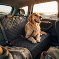 Happy golden retriever sitting on waterproof dog car seat cover looking out window on road trip