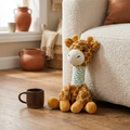 Knotted Crew plush giraffe rope toy for dogs sitting against a cream sofa on warm oak floor — Pethood